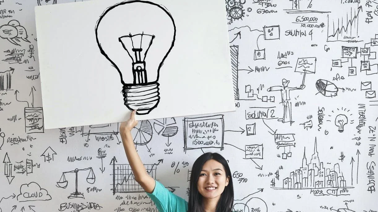 woman draw a light bulb in white board
