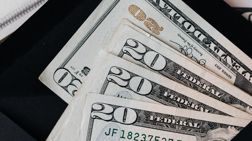 stack of dollars and black envelope with banknotes inside